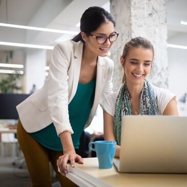 Zwei Personen schauen zusammen aud einen Laptop im Büro